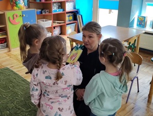 Trzy dziewczynki dają coś do ręki policjantce.
