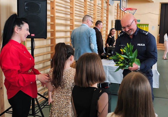 Komendant Policji wręcza paniom i dziewczynkom kwiaty.