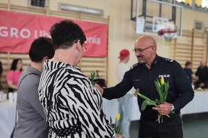 Komendant Policji wręcza paniom z publiczności kwiaty.