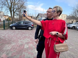 Policjant pokazuje kobiecie jak obsługiwać gaz pieprzowy.