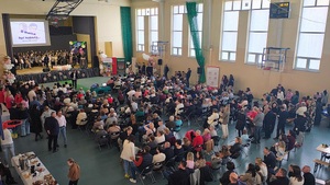 Sala sportowa na której jest uroczystość. Publiczność siedzi tyłem do zdjęcia, przodem do sceny.