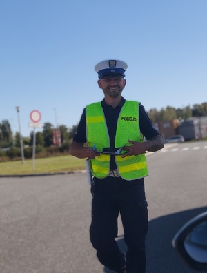 Policjant ruchu drogowego idzie uśmiechnięty w stronę zdjęcia.