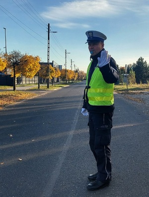 Policjant ruchu drogowego na drodze kieruje ruchem.