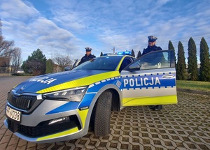 Dwaj policjanci przy oznakowanym radiowozie.