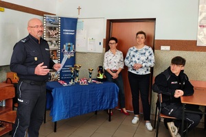 Klasa w szkole, komendant Policji mówi do zebranych. Koło komendanta stoją panie dyrektorki ze szkoły.