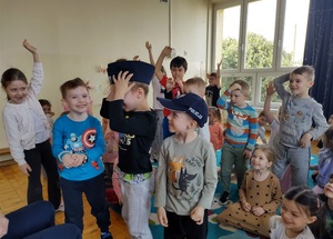 Dzieci przymierzają czapki policyjne.