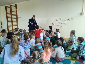 Policjantka rozdaje dzieciom kolorowanki.