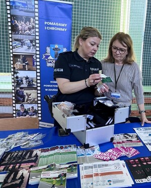 Policjantka rozmawia z kobietą, pokazuje jej coś małego.