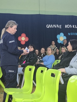 Policjantka pokazująca zawartość walizki edukacyjnej rodzicom uczniów i nauczycielom.