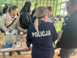 Osoby biorące udział w spotkaniu z policjantką, oglądające z bliska zawartość walizki edukacyjnej.