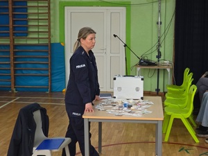 Umundurowana policjantka prowadząca prelekcję dla rodziców na temat uzależnień wśród dzieci i młodzieży.