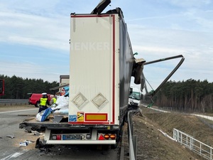 Na drodze stoi do połowy zniszczona przyczepa ciężarowa.