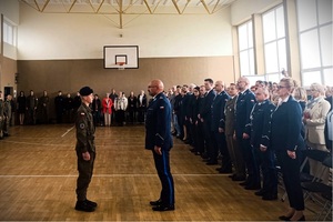 Sala gimnastyczna w szkole. Dowódca uroczystości składa meldunek komendantowi.