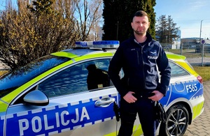 Przy radiowozie stoi policjant