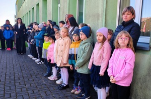 Uczniowie stoją przed szkołą.