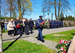 Komendant Powiatowy Policji składa kwiaty pod tablicą.