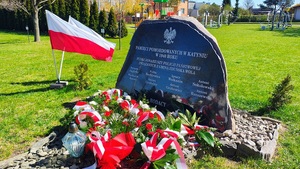 Tablica pamiątkowa z nazwiskami pomordowanych, pod tablicą złożone kwiaty.