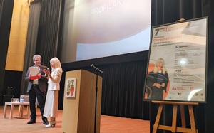 Na scenie stoi mężczyzna i kobieta, mówią do publiczności.