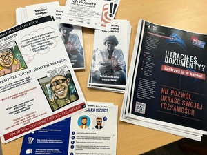 Na stoliku leżą różne ulotki promujące bezpieczeństwo w domu i na drodze.