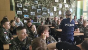 Klasa w szkole. Policjantka stoi między ławkami, w których siedzą uczniowie.
