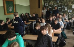 Klasa w szkole. Policjantka stoi między ławkami, w których siedzą uczniowie.