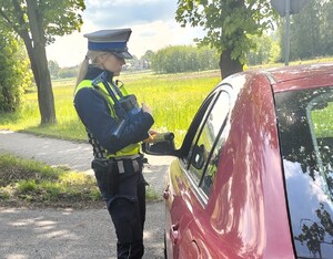 Policjantka stoi obok samochodu, rozmawia z kierowcą.