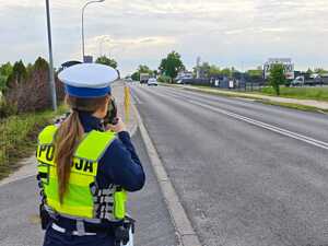 Policjantka patrzy przez urządzenie do pomiaru prędkości pojazdów.