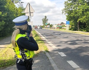 Policjantka patrzy przez urządzenie do pomiaru prędkości pojazdów.