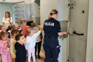 Policjantka otwiera drzwi do policyjnej celi.