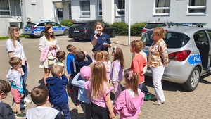 Policjantka rozdaje dzieciom odblaskowe przywieszki.