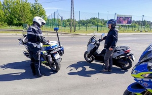 Policjant stoi obok motoru, przy nim stoi mężczyzna ze skuterem.