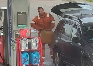 Na stacji paliw między samochodem, a dystrybutorem, stoi mężczyzna, w rękach trzyma kanister na paliwo.