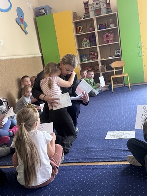 Przedszkolak tulący się do umundurowanej policjantki i wręczający laurkę.