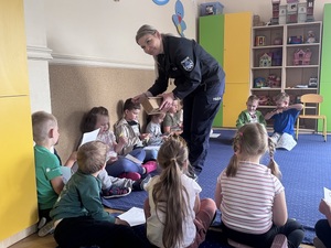 Policjanta rozdająca dzieciom elementy odblaskowe.
