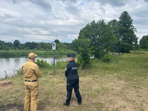 Policjantka ze strażakiem kontrolująca kąpielisko z zakazem kąpieli.