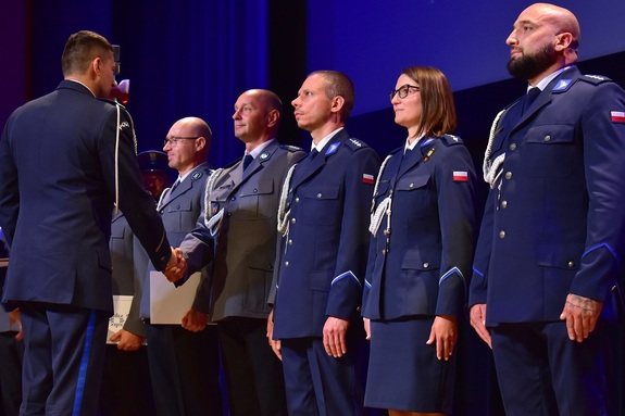 Trwa uroczystość. Na scenie policjanci otrzymują akty mianowania.