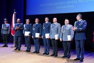 Trwa uroczystość. Na scenie policjanci otrzymują akty mianowania i pozują do zdjęcia.