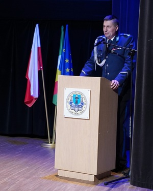Za mównicą stoi policjant, mówi do zebranych.