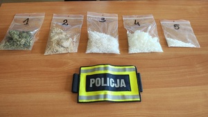 Pięć torebek foliowych z zawartością różnych substancji odurzających leżące na stole.