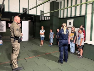 Dwoje policjantów i dzieci są na strzelnicy.