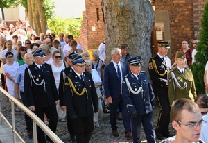 Komendant razem z tłumem ludzi idzie wzdłuż budynku.