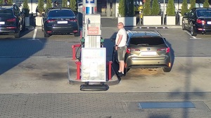 Stacja paliw. Przy dystrybutorze koło samochodu stoi mężczyzna.