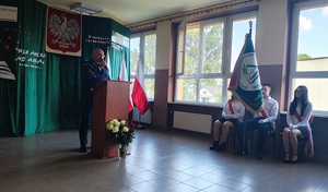 Za mównicą stoi policjant, mówi do zebranych.