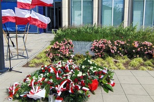 Tablica upamiętniająca zamordowanych Zduńskowolan. Wokół są wiązanki kwiatów i znicze.