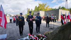 Przedstawiciele służb mundurowych składają kwiaty przed pomnikiem.