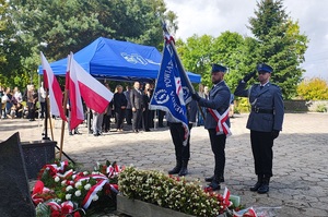Poczet sztandarowy policjantów, oddaje cześć przed pomnikiem.