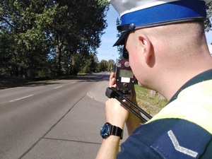 Umundurowany policjant dokonujący statycznego pomiaru prędkości.