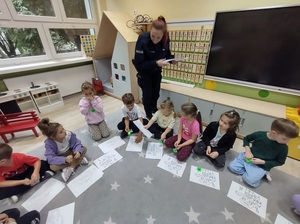 Policjantka rozdająca dzieciom malowanki.