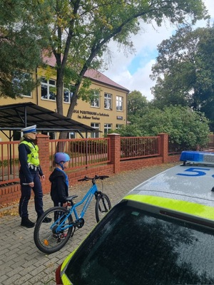 Policjantka z chłopcem, który poruszał się na rowerze i otrzymał kask od policjantów.