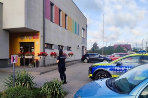 Policjantka i radiowóz przed szkołą.